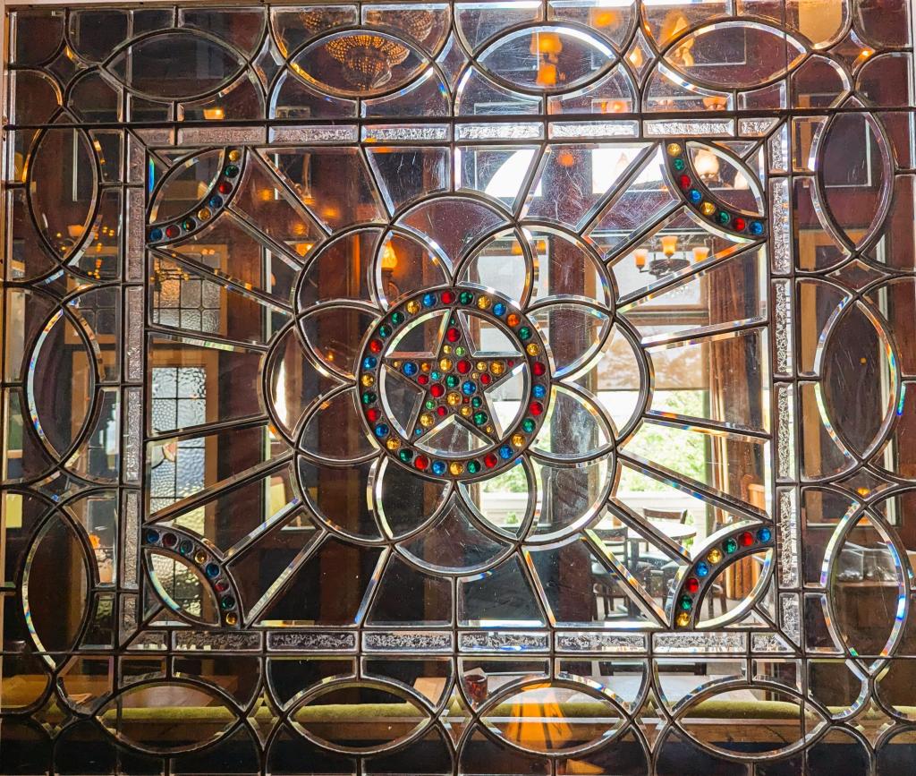 Photo of a stained glass window with a centre start filled with multi-coloured transparent beads.